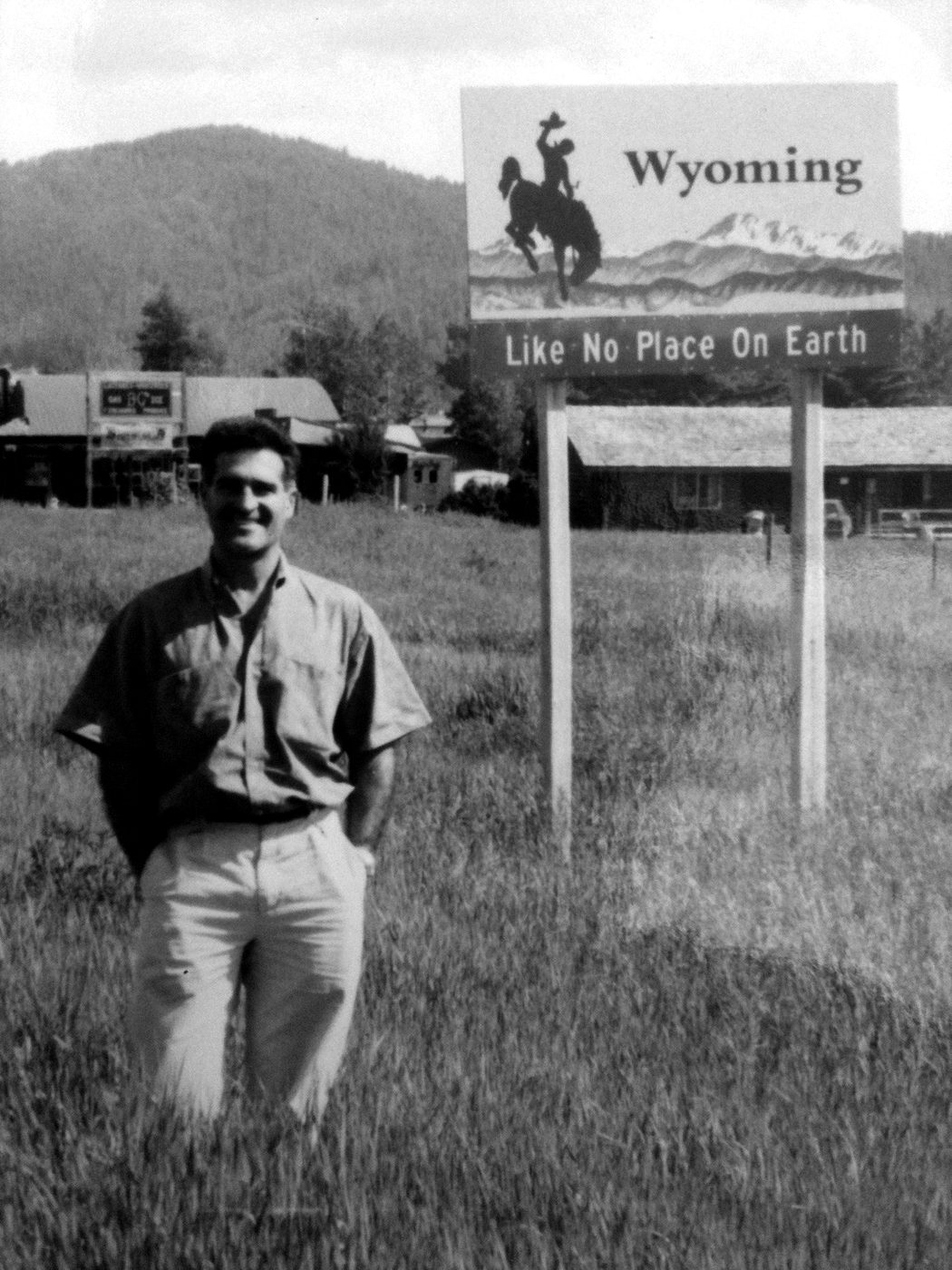 A young Kevin Seney standing beside a Wyoming state welcome sign