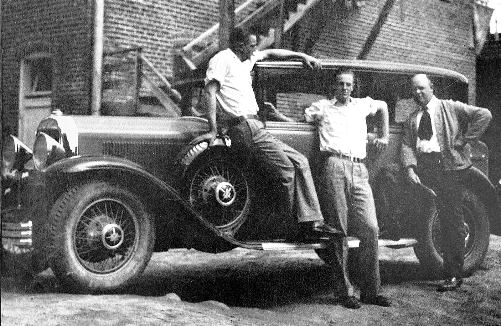 Three men with an old car behind a brick drugstore in Buffalo, Wyoming